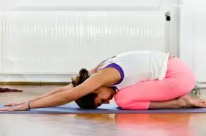 Woman performing child's pose to highlight restful physiotherapy exercises for lower back pain decompression.