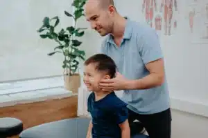 A physiotherapist assesses a young patient as part of a clinical appointment, which may include movement assessment and hands-on care.