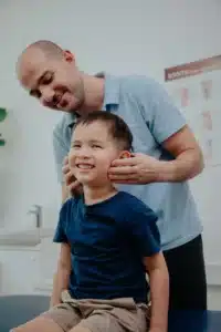 A physiotherapist assesses a young patient as part of a clinical appointment, which may include movement assessment and hands-on care.