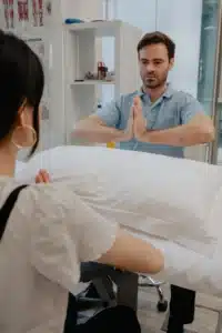 A physiotherapist demonstrating a prayer stretch for the wrists.